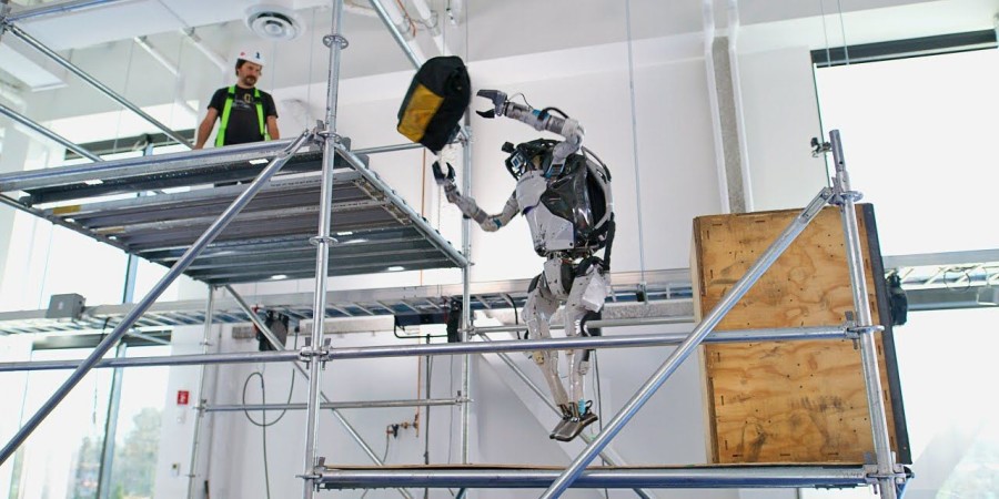 Le robot humanoide Atlas en train de lancer un sac d’outils a un ouvrier sur un echaffaudage 