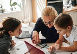 une femme apprenant a ses filles a manipuler un ordinateur
