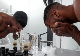 Un homme en train de se laver le visage devant le miroir