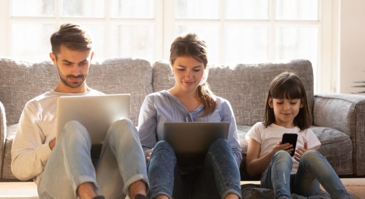 Un homme, une femme et une fille navigant sur un ordinateur, une tablette et un smartphone