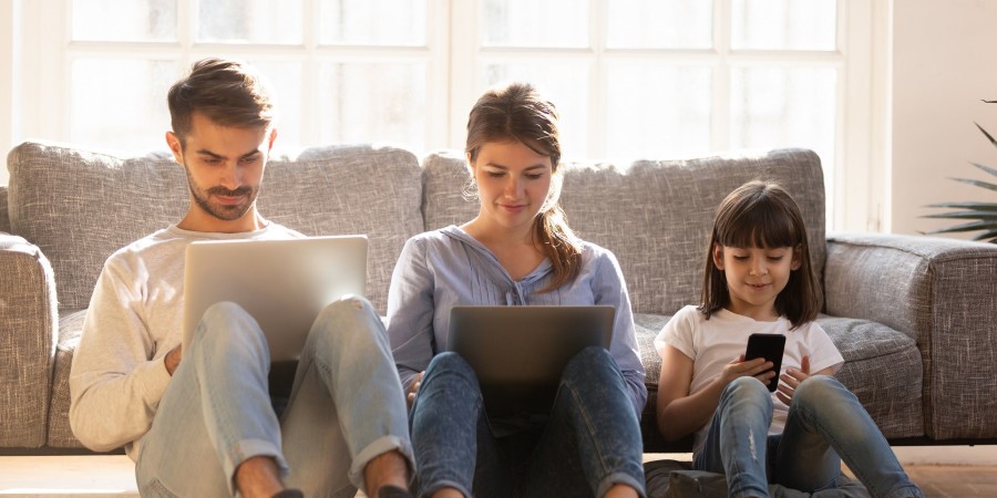 Un homme, une femme et une fille navigant sur un ordinateur, une tablette et un smartphone 