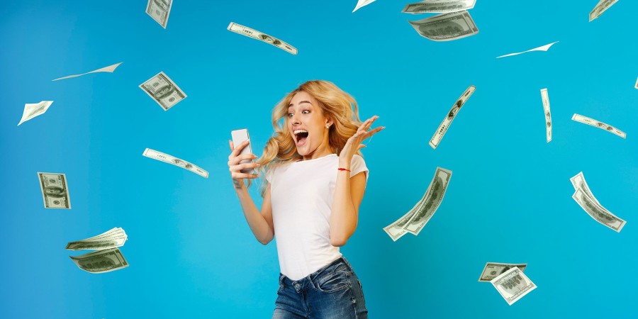 Une femme criant de joie en regardant son telephone avec des billets d’argent qui tombent autour d’elle 