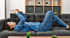 Une femme allongee sur le sofa en train de naviguer sur son smartphone