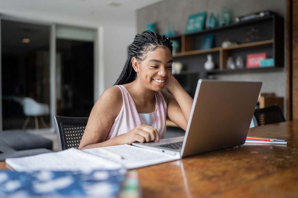 Une jeune étudiante souriant devant son ordinateur 