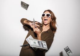 Une femme portant des lunettes solaires riant et eparpillant des billets d’argent