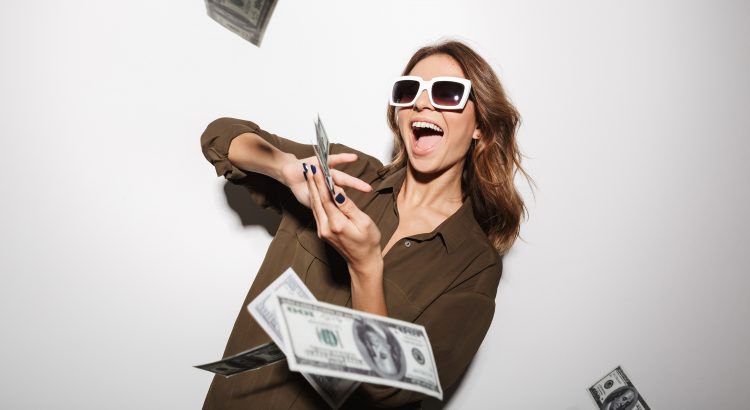 Une femme portant des lunettes solaires riant et eparpillant des billets d’argent