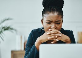 Une femme pensive fixant serieusement l’ecran de son ordinateur