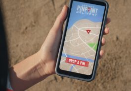 Une main tenant un smartphone affichant la page de livraison par geolocalisation de Domino’Pizza