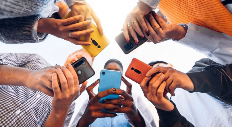 Photo prise d’en bas de cinq personnes formant un cercle et tenant leur smartphone