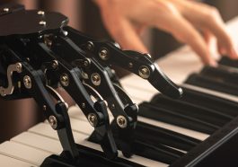 Une main de robot et une main humaine jouant du piano