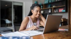 Une jeune femme souriant en train de travailler sur son ordinateur portable