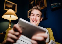 Un jeune homme riant en fixant sur sa tablette numerique