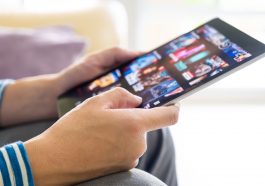 Mains d’un homme tenant une tablette numerique affichant une plateforme streaming video