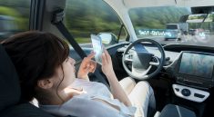 Une femme au volant d’une voiture autonome tout en manipulant son smartphone